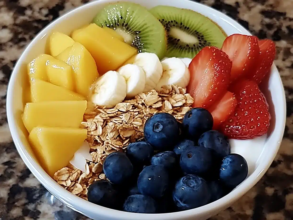 A vibrant smoothie bowl topped with fresh berries, granola, sliced kiwi, and shredded coconut, served in a white bowl on a wooden table.