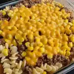 A hearty and cheesy Loaded Cowboy Cheeseburger Casserole served in a baking dish, topped with melted cheddar and garnished with fresh herbs.