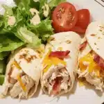 A crispy Chicken Bacon Ranch Wrap filled with juicy chicken, crispy bacon, fresh lettuce, tomatoes, shredded cheddar cheese, and creamy ranch dressing, wrapped in a golden-brown tortilla.